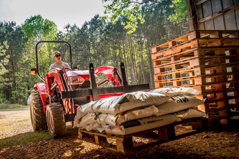 A farmer lifts bags of seed on a pallet with a Massey Ferguson 2860E